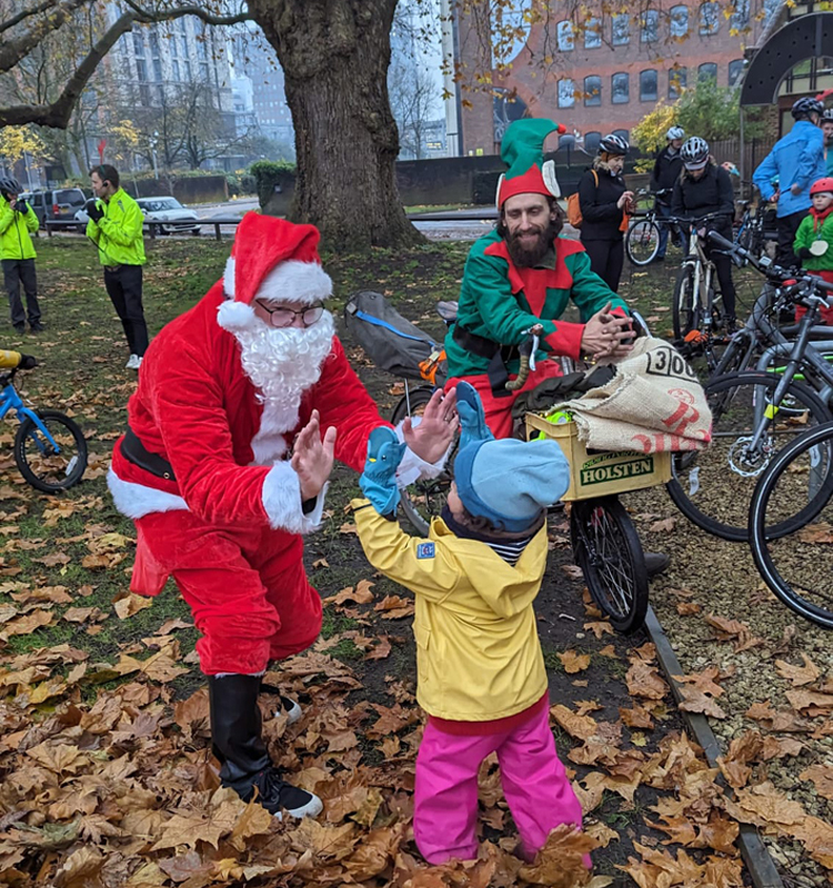 Santa hi-fiving a child at a Kidical Mass ride